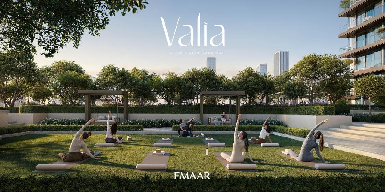 Outdoor yoga session on a lawn at Valia, city towers in the background