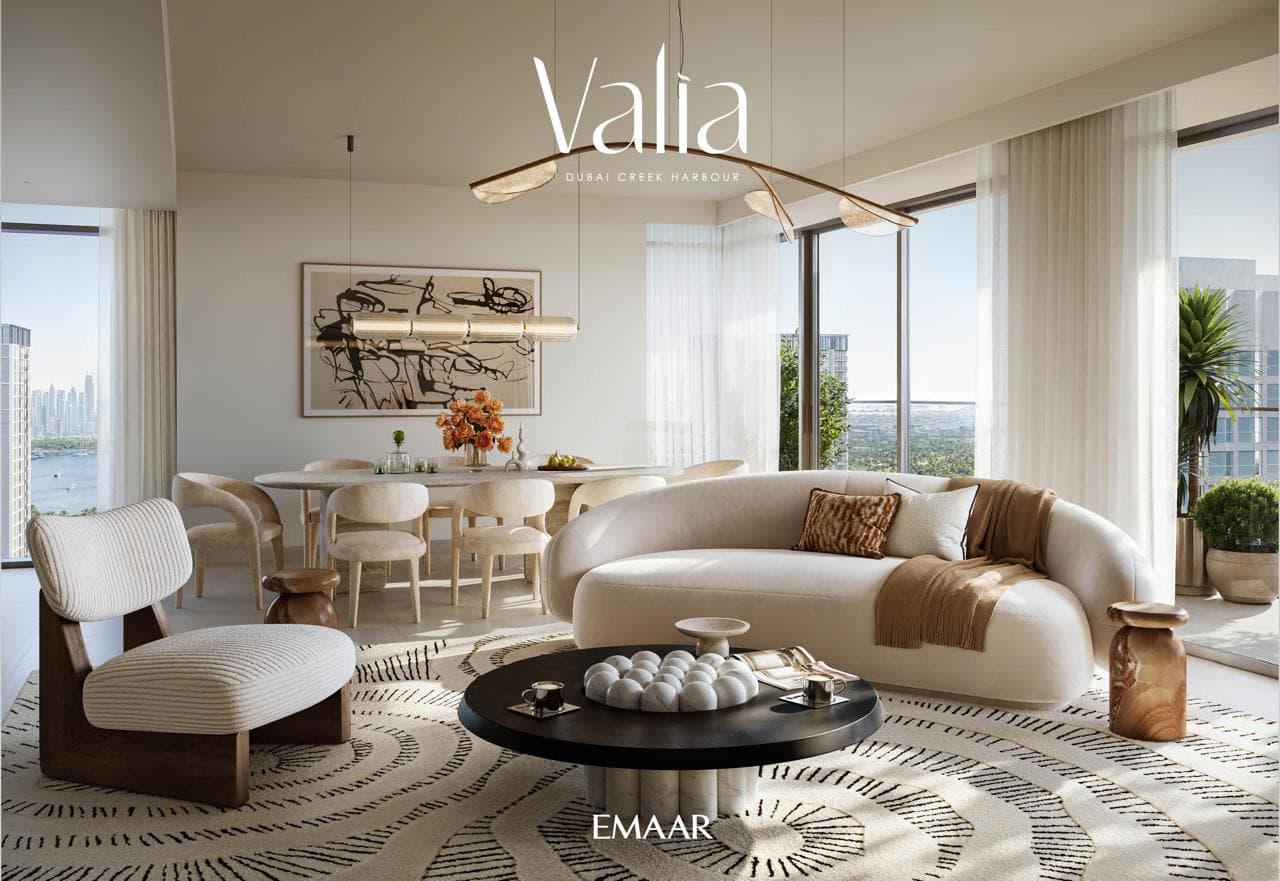 Furnished living and dining room in a Valia apartment with a water view through floor-to-ceiling windows